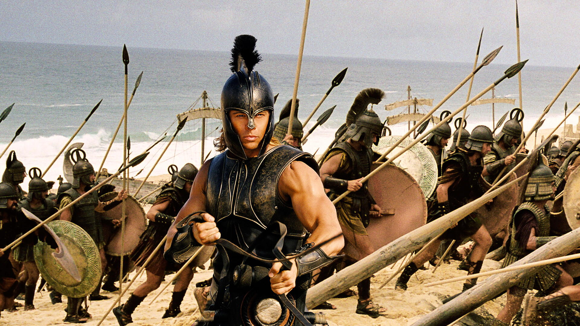 Scene from Troy: Trojan warriors in bronze armor charging across a sandy beach, spears raised — 4K Ultra HD PC desktop wallpaper and background.