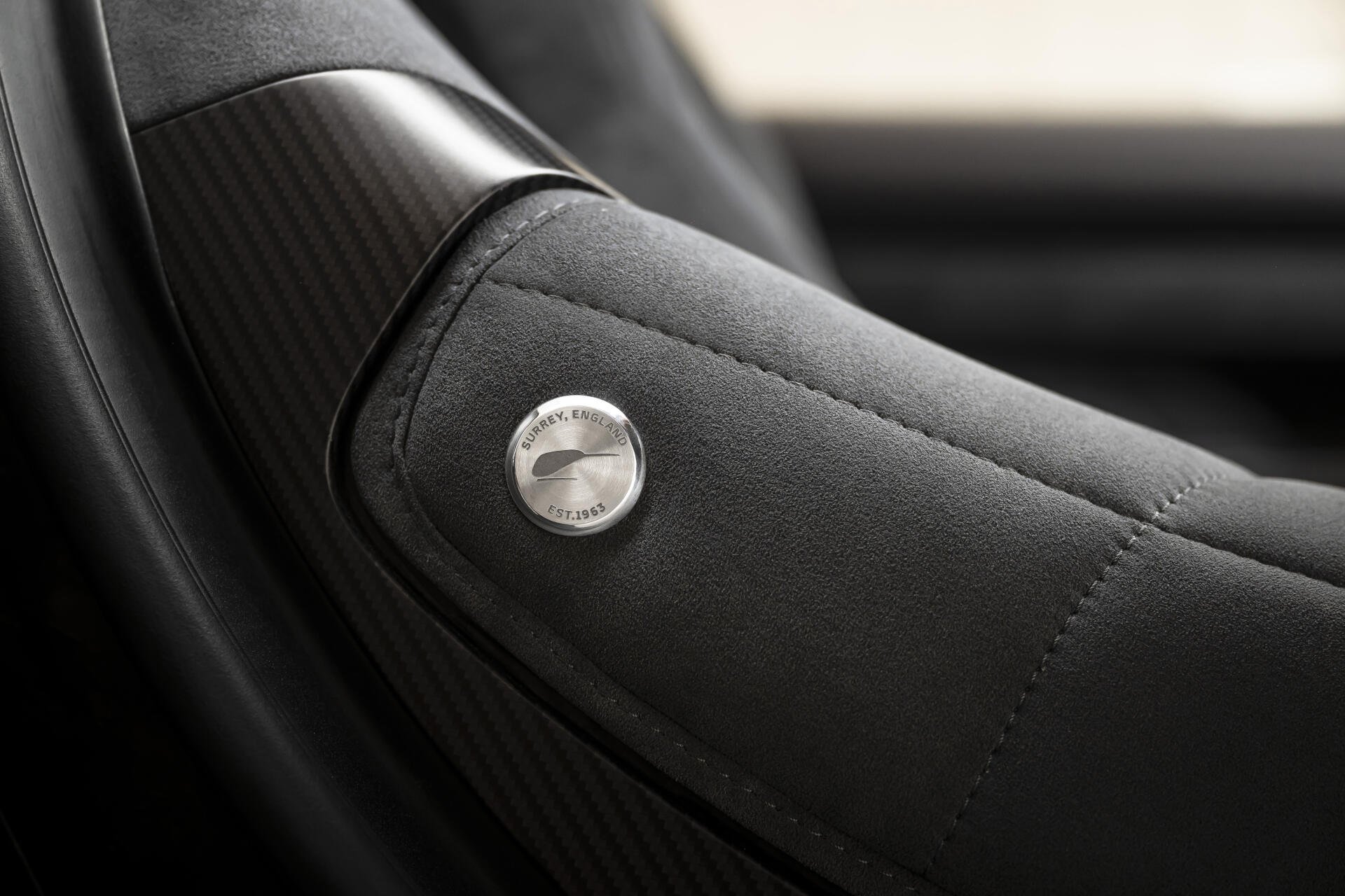 Close-up of McLaren McL 6GT leather car seat armrest with stitched detail, 8K Ultra HD PC desktop wallpaper background.