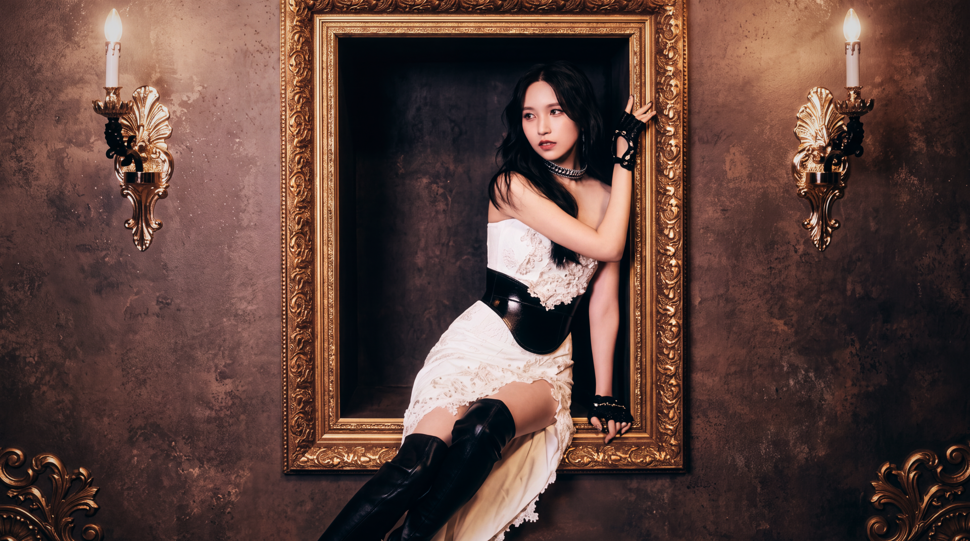 Young woman in a white lace dress and black thigh-high boots posed inside an ornate gold frame on a vintage wall lit by two sconces — 5K desktop wallpaper.