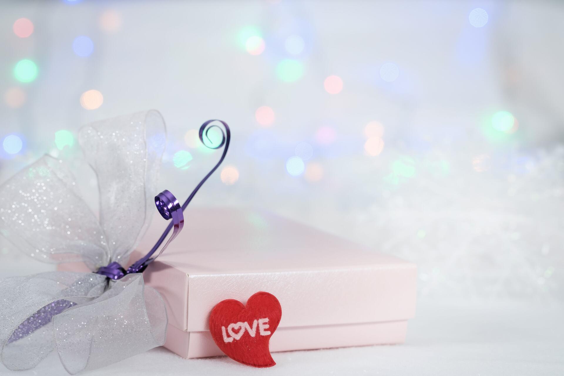 4K Ultra HD PC wallpaper: aesthetic gift scene — pastel present with purple ribbon and red heart reading LOVE set against a soft electric yellow bokeh background.
