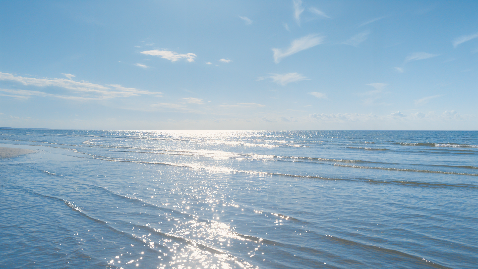 End-of-summer ocean beach beneath a bright blue sky, 4K Ultra HD PC desktop wallpaper and background.