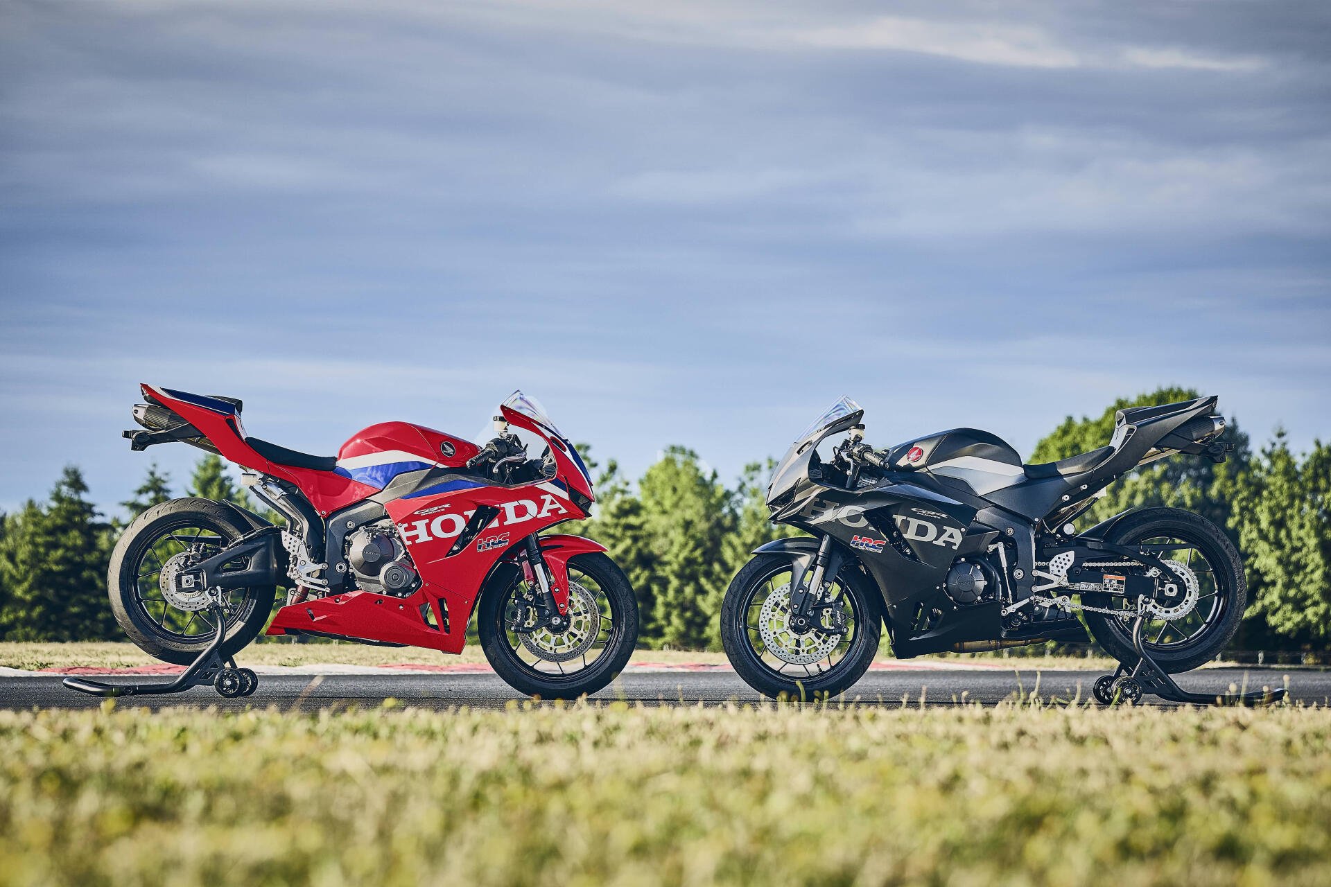 Red Honda CBR600RR and black Ducati sport bikes parked side by side, 4K Ultra HD desktop wallpaper.