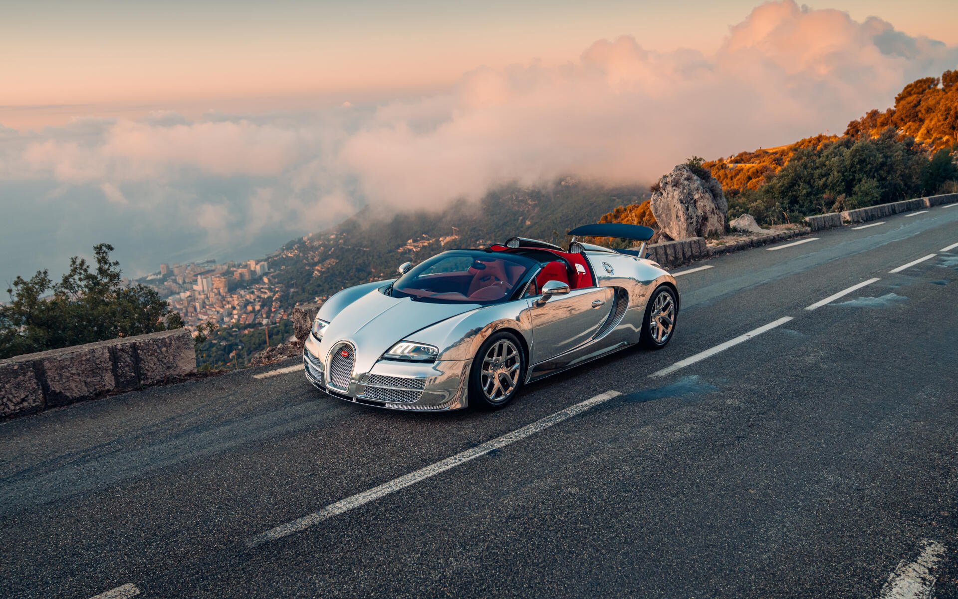 Silver Bugatti Veyron Grand Sport Vitesse convertible sports car on a mountain road at sunset, 5K Ultra HD desktop wallpaper.