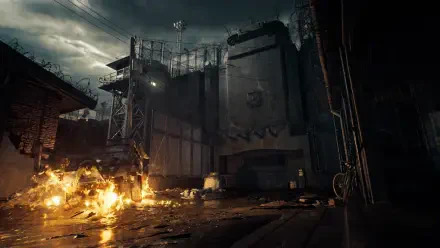 Moody, rain-soaked prison yard with burning wreckage — Resident Evil Veronica scene from the Resident Evil video game; 4K Ultra HD PC desktop wallpaper and background.