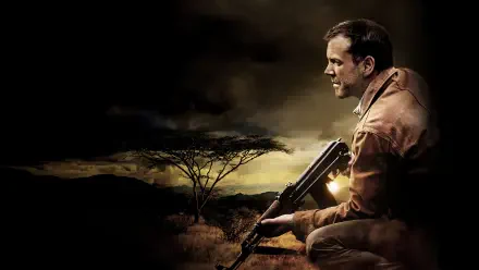 24 — 4K Ultra HD PC Desktop Wallpaper and Background: crouching man holding a rifle against a dusky African savanna, dramatic clouds and warm backlight.