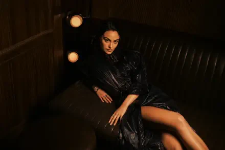 Celebrity actress lounging on a leather sofa in dramatic warm light, wearing a dark evening dress with exposed leg — 4K Ultra HD PC desktop wallpaper/background.