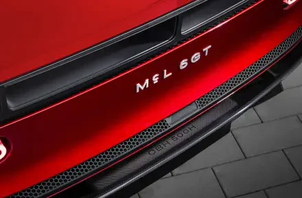 Close-up of red McLaren McL 6GT sports car rear bumper and badge, showing carbon trim and grille details — 5K Ultra HD PC desktop wallpaper background.