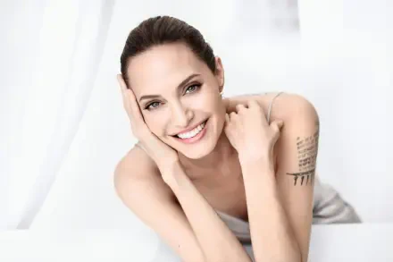 Bright 4K Ultra HD PC desktop wallpaper of a smiling woman reclining, bare-shouldered with an upper-arm tattoo, fresh-faced close-up studio portrait.