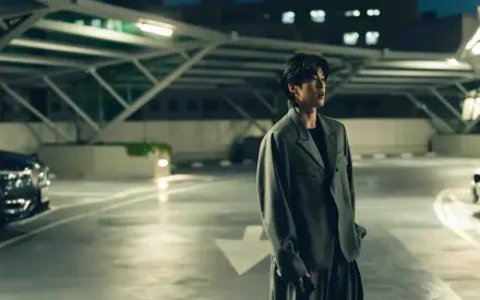 8K Ultra HD PC desktop wallpaper: lone man from The Fixers stands in a dim, cinematic parking garage with dramatic lighting and empty lanes.