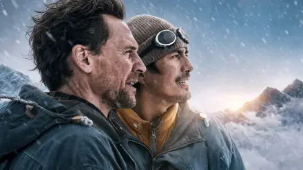 Two men in mountaineering gear gaze toward sunrise from a snowy mountain ridge; cinematic 4K Ultra HD PC desktop wallpaper.