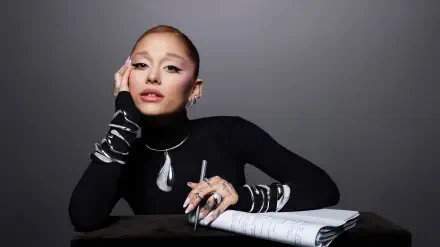Stylish female pop singer in black turtleneck, bold makeup and statement jewelry, posing with a notebook; 2K Quad HD PC desktop wallpaper evoking music and studio vibes.