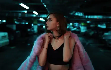 Female model in a pink fur coat and black crop top posing in a moody parking garage — 4K Ultra HD PC desktop wallpaper/background.