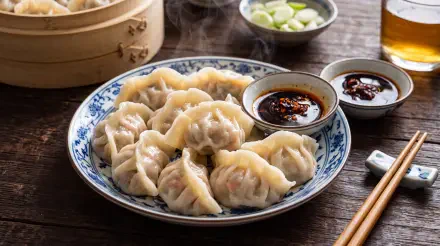 Steamed Chinese dumplings with dipping sauces on a wooden table, 5K Ultra HD PC desktop wallpaper and background.