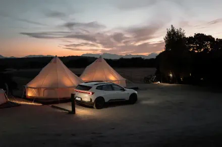 Polestar 4 SUV beside glowing glamping tents at sunset, 8K Ultra HD PC desktop wallpaper and background.