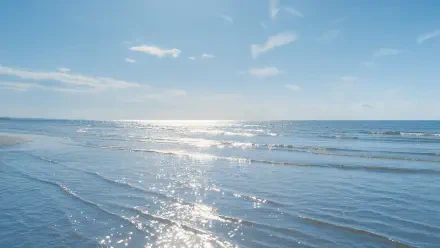 End-of-summer ocean beach beneath a bright blue sky, 4K Ultra HD PC desktop wallpaper and background.