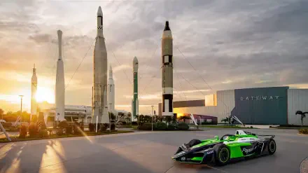 Envision Racing Formula E car at a space center with rockets, featured in an 8K Ultra HD desktop wallpaper.