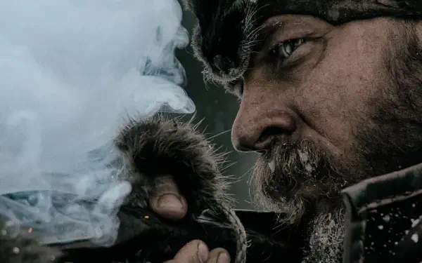 Close-up of a frost-bitten bearded frontiersman from The Revenant lighting a pipe amid snow — 4K Ultra HD PC desktop wallpaper/background.
