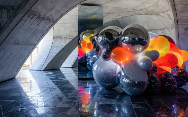 4K Ultra HD PC desktop wallpaper/background: modern sculpture installation — reflective chrome and colorful orb clusters beneath concrete arches, glossy floor reflections