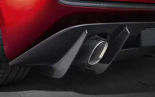Close-up of a red McLaren McL 6GT rear bumper with carbon-fiber diffuser and chrome exhaust tailpipe, 8K Ultra HD PC desktop wallpaper background.