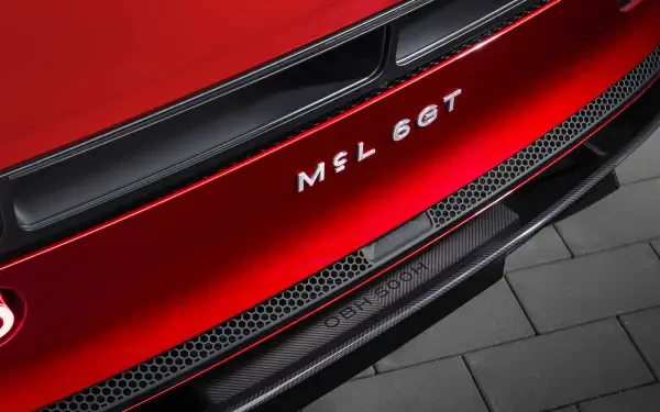 Close-up of red McLaren McL 6GT sports car rear bumper and badge, showing carbon trim and grille details — 5K Ultra HD PC desktop wallpaper background.