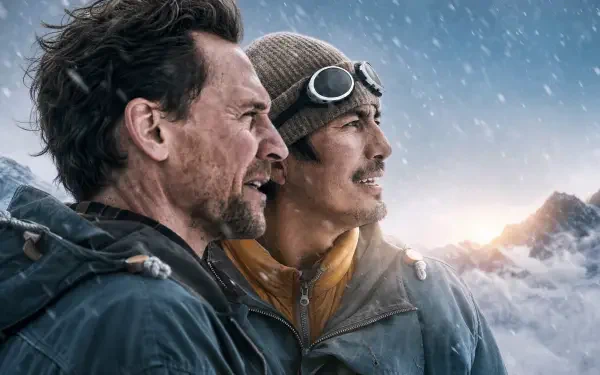 Two men in mountaineering gear gaze toward sunrise from a snowy mountain ridge; cinematic 4K Ultra HD PC desktop wallpaper.