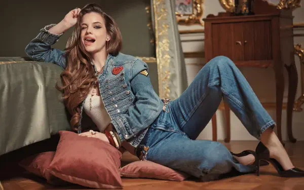 4K Ultra HD PC desktop wallpaper of a woman in a denim jacket and jeans reclining on pillows in an ornate room, smiling and posing casually.