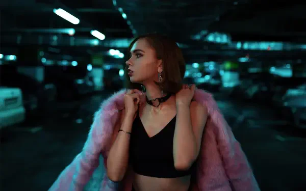 Female model in a pink fur coat and black crop top posing in a moody parking garage — 4K Ultra HD PC desktop wallpaper/background.