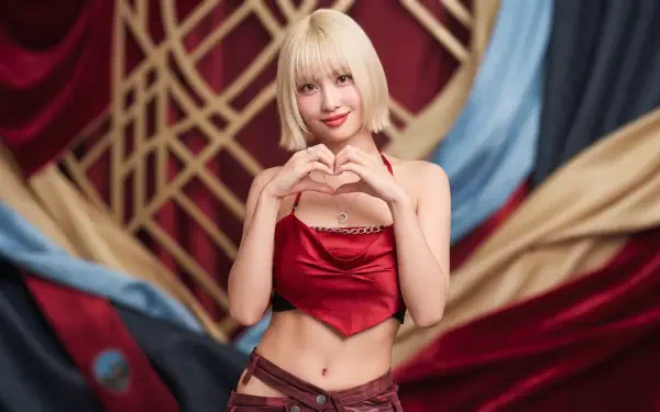 Blonde woman in a red satin crop top forming a heart with her hands against an ornate draped backdrop — 5K Ultra HD PC desktop wallpaper with K-pop–inspired styling.
