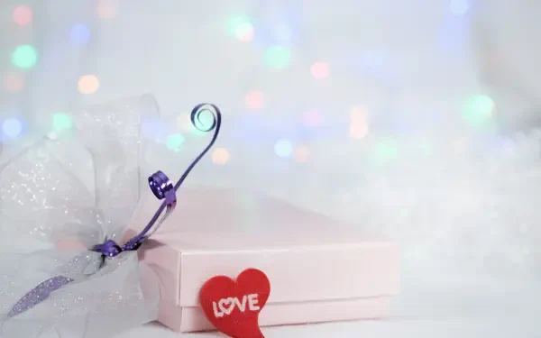 4K Ultra HD PC wallpaper: aesthetic gift scene — pastel present with purple ribbon and red heart reading LOVE set against a soft electric yellow bokeh background.
