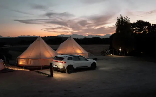 Polestar 4 SUV beside glowing glamping tents at sunset, 8K Ultra HD PC desktop wallpaper and background.