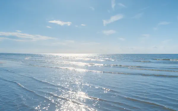 Sunlight sparkles across a calm ocean at the end of summer in this 4K Ultra HD PC desktop wallpaper and background.