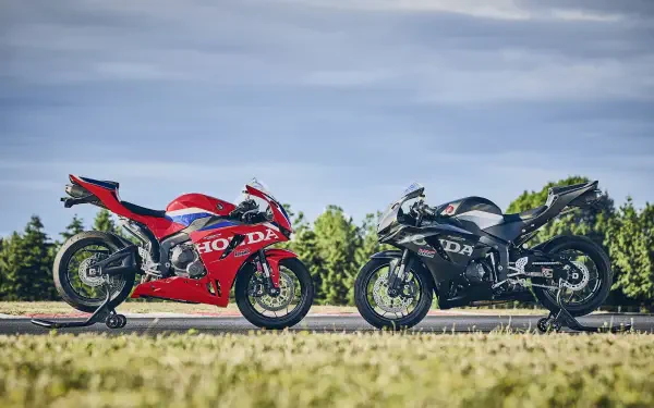 Red Honda CBR600RR and black Ducati sport bikes parked side by side, 4K Ultra HD desktop wallpaper.