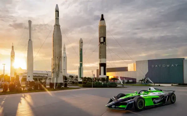 Envision Racing Formula E car at a space center with rockets, featured in an 8K Ultra HD desktop wallpaper.