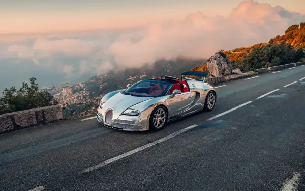 Silver Bugatti Veyron Grand Sport Vitesse convertible sports car on a mountain road at sunset, 5K Ultra HD desktop wallpaper.