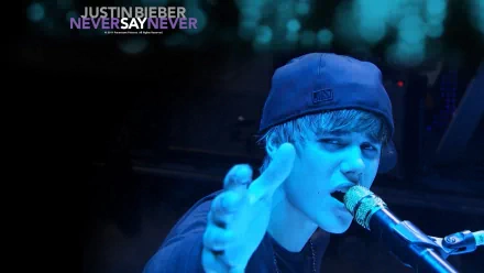 HD desktop wallpaper of Justin Bieber performing on stage with a microphone, tagged with 'Never Say Never' in the background. The image has a blue tint.