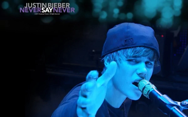 HD desktop wallpaper of Justin Bieber performing on stage with a microphone, tagged with 'Never Say Never' in the background. The image has a blue tint.