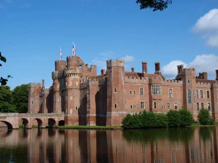 A stunning HD desktop wallpaper featuring Herstmonceux Castle, showcasing its impressive architecture and reflected in the serene waters surrounding it.