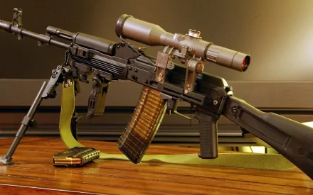 HD desktop wallpaper featuring a Kalashnikov AK-101 assault rifle with a scope, resting on a wooden surface next to a magazine.