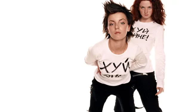 HD PC desktop wallpaper showing a music duo posing on a white background: two women in white shirts with bold lettering, one leaning forward in an energetic portrait.