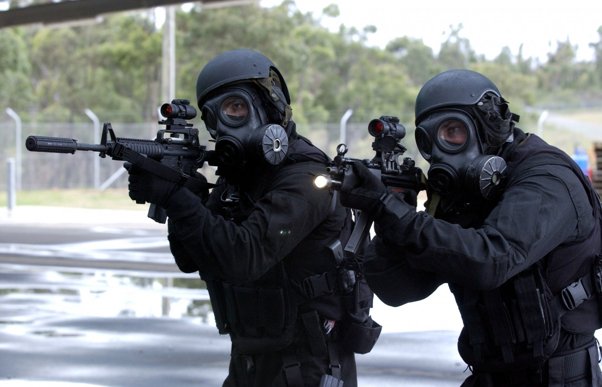 Two Special Forces soldiers in tactical gear and gas masks aim rifles during a military operation, captured in an HD PC desktop wallpaper image.