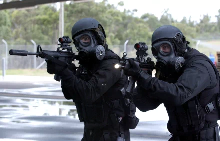 Two Special Forces soldiers in tactical gear and gas masks aim rifles during a military operation, captured in an HD PC desktop wallpaper image.
