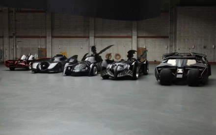 HD desktop wallpaper showcasing various Batmobile designs from The Dark Knight series lined up in a spacious garage.