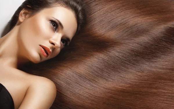 A stunning 4K Ultra HD wallpaper featuring a woman with beautifully styled long brown hair, elegantly arranged around her, showcasing her captivating expression.