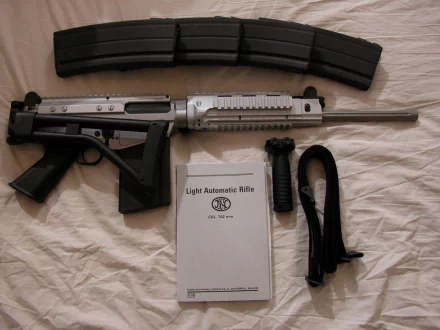 A high-definition desktop wallpaper featuring a submachine gun, accompanied by a magazine and a manual titled Light Automatic Rifle. The setting emphasizes a sleek, tactical aesthetic.