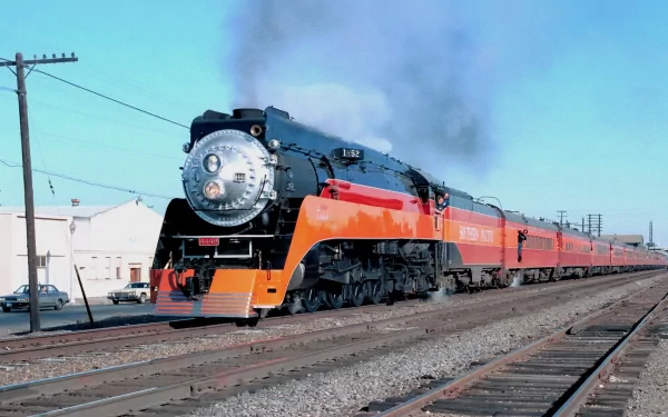 HD wallpaper of the Southern Pacific 4449 Daylight steam locomotive pulling passenger cars along a sunlit track under a clear blue sky.