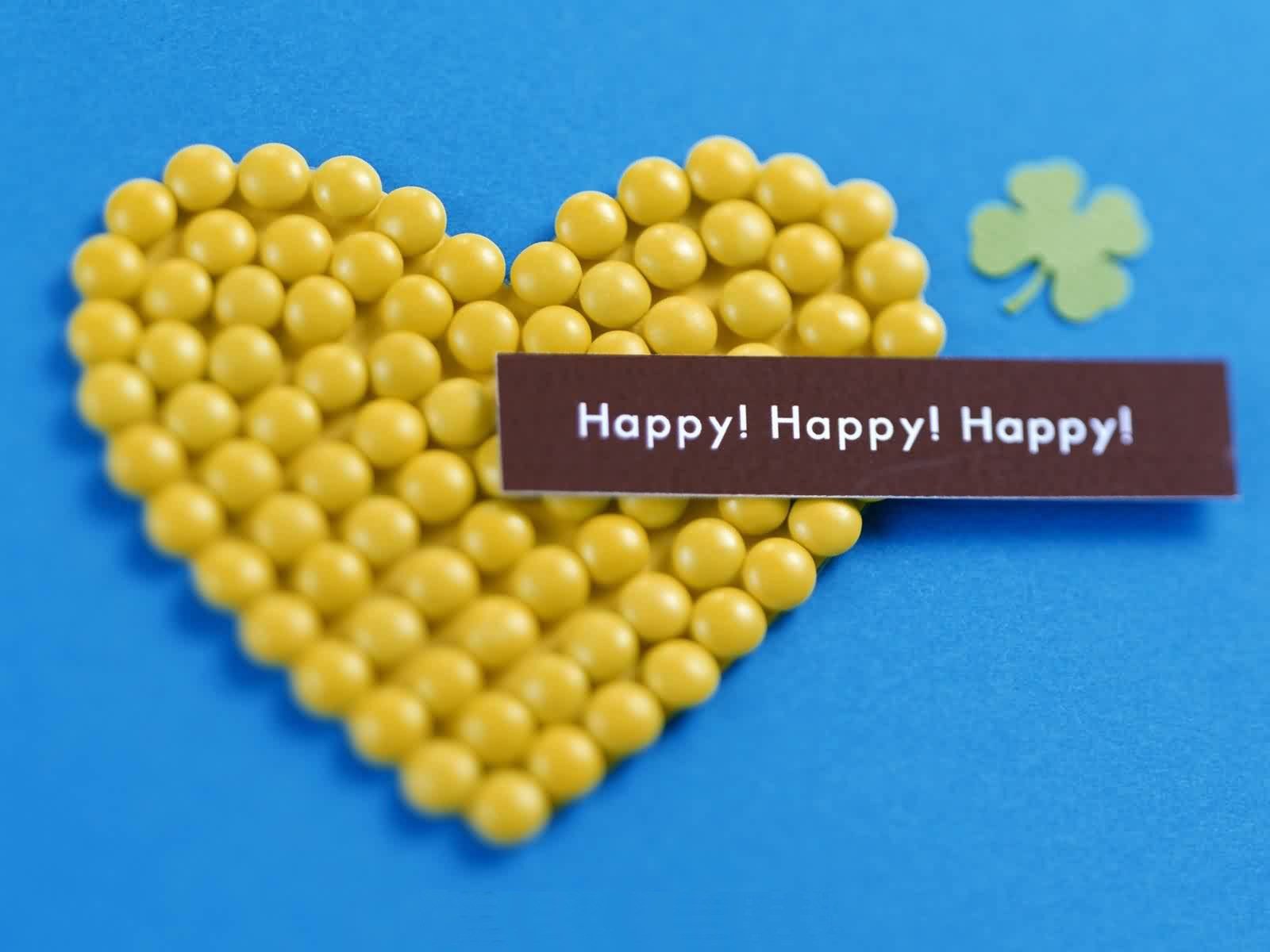 A vibrant HD desktop wallpaper featuring a heart made of yellow beads on a blue background, accompanied by a message of joy and a small green clover, celebrating love and happiness.
