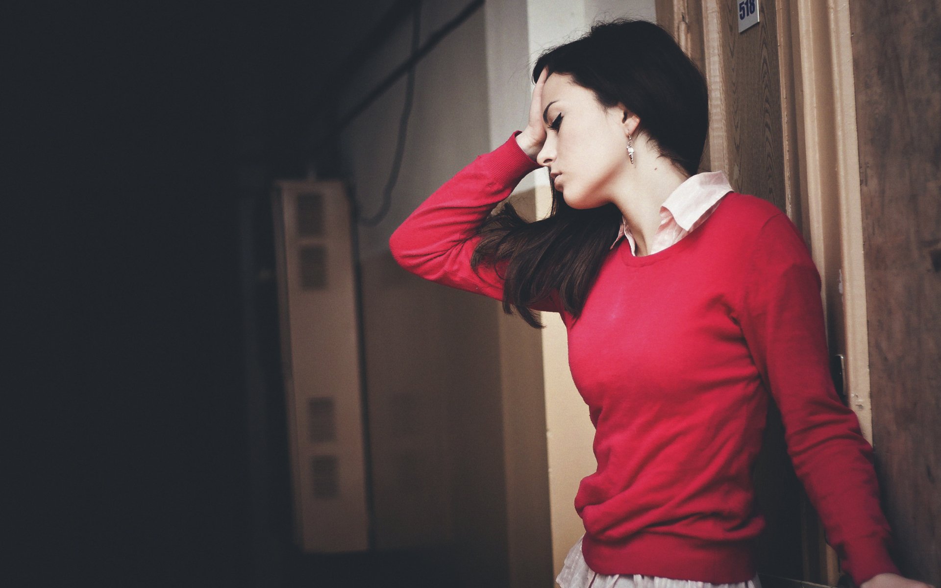 HD PC desktop wallpaper featuring a woman model in a red sweater, posing thoughtfully against a muted indoor background.
