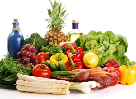 A vibrant arrangement of fresh vegetables and fruits, including peppers, grapes, and leafy greens, complemented by olive oil and a pineapple, creating a colorful and appetizing desktop background.