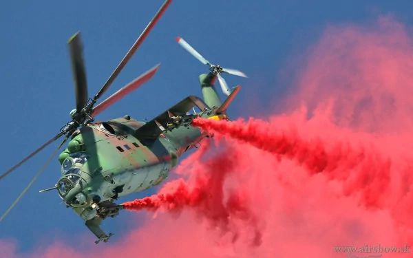 HD desktop wallpaper featuring a Mil Mi-24 military helicopter releasing vibrant red smoke against a clear blue sky.