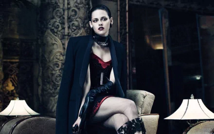 A striking HD desktop wallpaper featuring Kristen Stewart, showcasing her in a dramatic outfit with a bold look, seated gracefully in an elegant setting with stylish lighting.